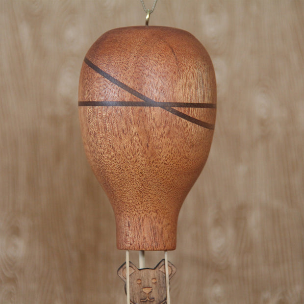 Wooden sculpture of a hot air ballon with a small bear sitting in the basket. 