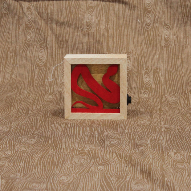 Small wooden shadowbox with a red snake inside of the box. A button is on the right side of the box, used to turn on and off a light.