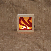 Small wooden shadowbox being illuminated by a warm light in the back. A red snake fits inside of the box, where the light shines behind it.