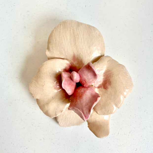 Ceramic orchid flower, an off white color with a pink center.