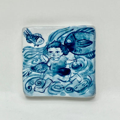 Square porcelain tile with rounded edges and an illustration in blue of a small girl running through rolling waves with fish swimming around.