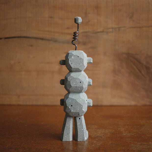 Painted whittled wooden sculpture of 3 eyeball stone monsters stacked atop of each other with an antenna on the top of its head.