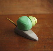 Painted assembled whittled wood sculpture of a gray snail with a green swirled shell and 2 large feelers atop its head.