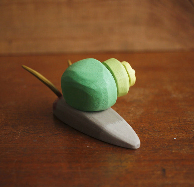 Painted assembled whittled wood sculpture of a gray snail with a green swirled shell and 2 large feelers atop its head.