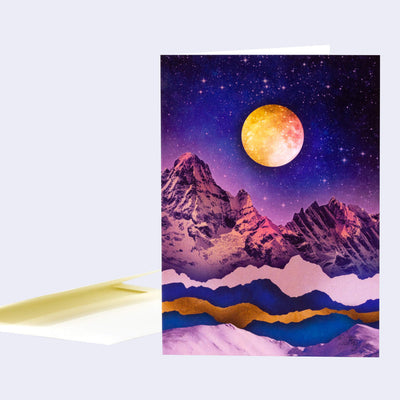 Greeting card with an illustration of a purple night sky over a pink mountain range. A large orange/red moon hangs in the sky. 