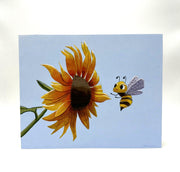 Painting of a large orange sunflower with a small cartoon bee flying up to it. Background is light blue.