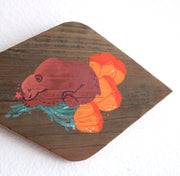 Painting on a diamond shaped piece of wood. Painting is of a cute brown bear sleeping on top of several orange poppy flowers.