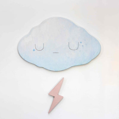 2 die cut wooden panels, one shapes like a cloud and painted light blue with a simple closed eye expression. Below, is a champagne pink colored lightning bolt.