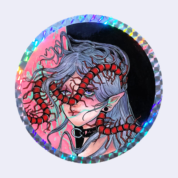 Circular sticker with a holographic border of a girl with elf ears, long gray straight hair and a collar. A large red and black centipede wraps around her head.