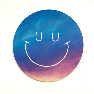 Circular panel painted like a deep blue, purple to orange sunset. A simple, cute closed eye smiley face is drawn in white paint atop.