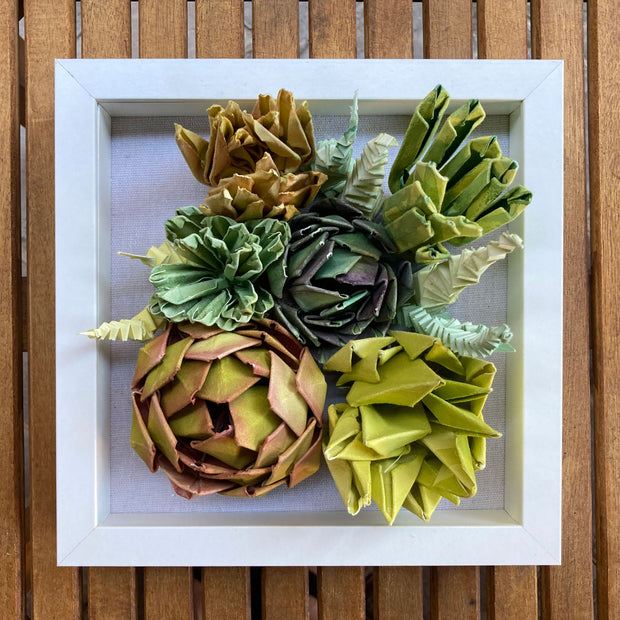 Open shadowbox featuring a 3D paper sculpture of a series of succulents.