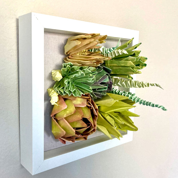 Open shadowbox featuring a 3D paper sculpture of a series of succulents.