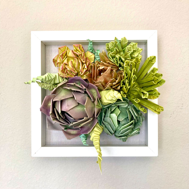 Open shadowbox featuring a 3D paper sculpture of a series of succulents.