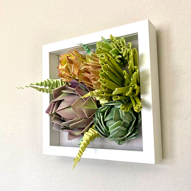 Open shadowbox featuring a 3D paper sculpture of a series of succulents.