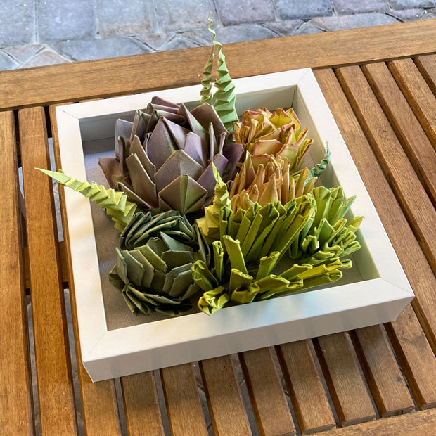 Open shadowbox featuring a 3D paper sculpture of a series of succulents.