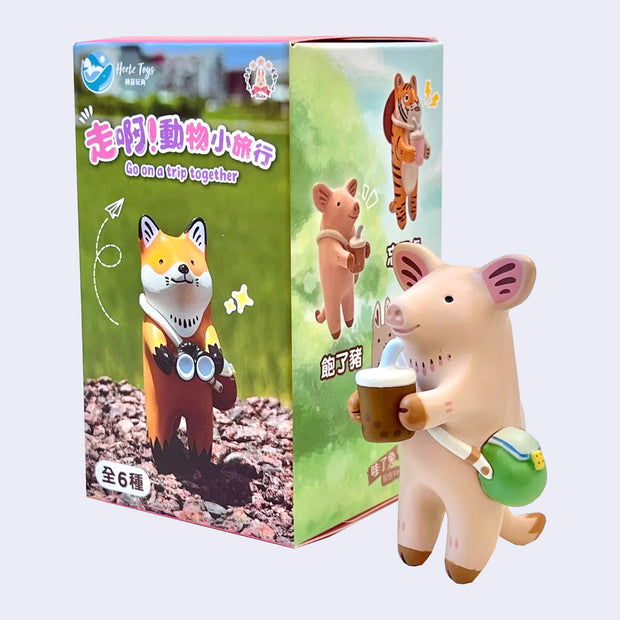 Small figure of a pig, standing on its hind legs with a cross body pouch and a cup of boba in its hands. It smiles and stands next to its product packaging.