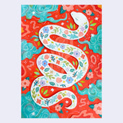 Paper cut art of a white snake with various flowers and leaves on its body in a pattern. Background is bright red with teal blue clouds and cut paper leaves and flowers.