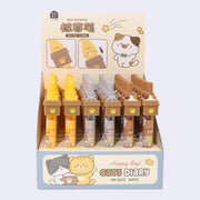 6 retractable pens with cats inside of cardboard boxes as the pen toppers. Cats are either gray on gray pens, calico on brown pens, or orange on orange pen bodies. In their product packaging.