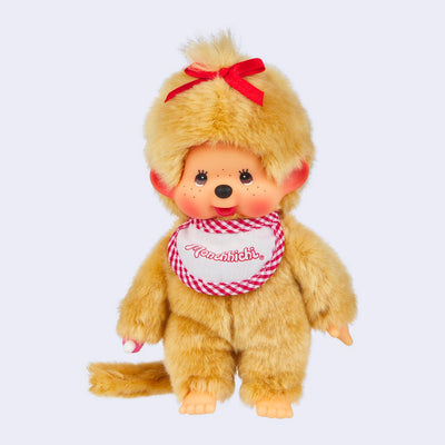 Plush doll of Monchhichi, a cute monkey that has a baby animal face with rosy cheeks and brown eyes. It has beige fluffy fur, wears a white and red plaid bib, red hair bow, and has a pacifier in its hand that can go in its mouth.