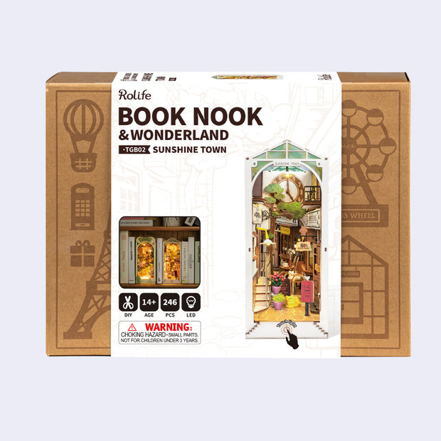 Product packaging of a 3D puzzle kit to build a bookend, with scenery of an alleyway containing bookshops and other shopping center visuals.