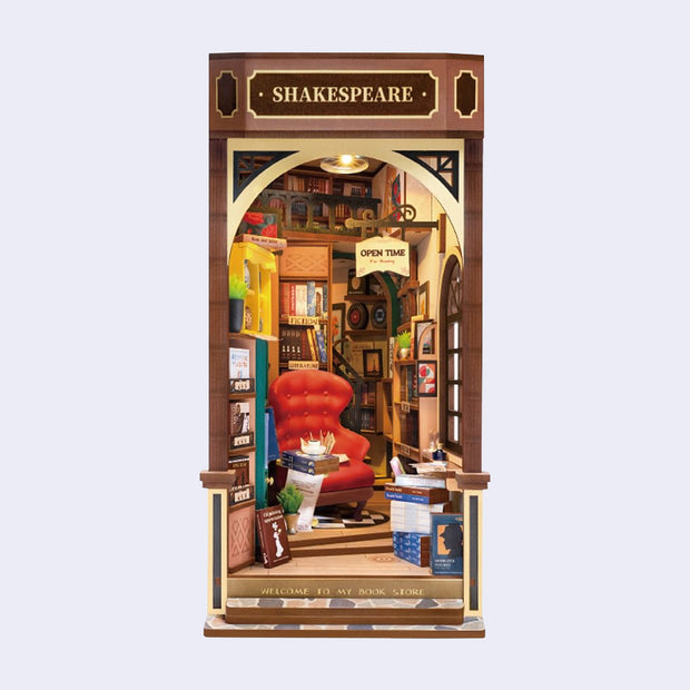 3D Booknook of a Shakespeare bookstore, with a big red arm chair and many rows of books around and behind. Contained within a rectangle that goes on a bookcase.