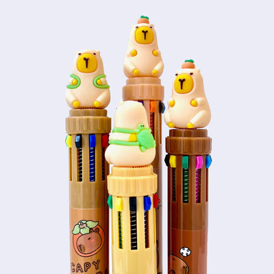 4 pens with 10 color options. Each pen is topped with a rubber capybara figure, 2 of them are wearing a turtle shaped backpack and the other 2 have a citrus atop their head.