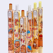 Close up of 6 pens with clicking mechanisms, .5 ink and wrap around designs of cartoon capybaras doing fun activities such as eating and playing. 