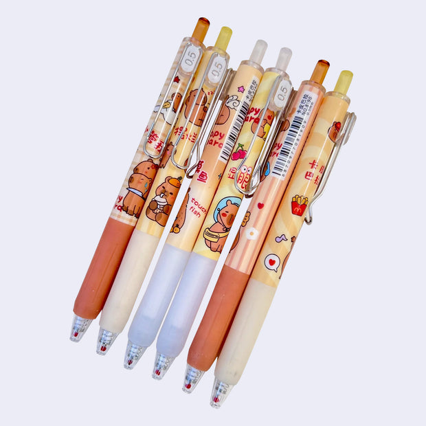 6 pens with clicking mechanisms, .5 ink and wrap around designs of cartoon capybaras doing fun activities such as eating and playing. 