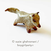 Small ceramic sculpture of a brown fox with a pointed snout, small ears and brown feet.