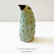 Mint green ceramic sculpture of a bird, standing without a lower body with an in set eyed and a black pointed beak