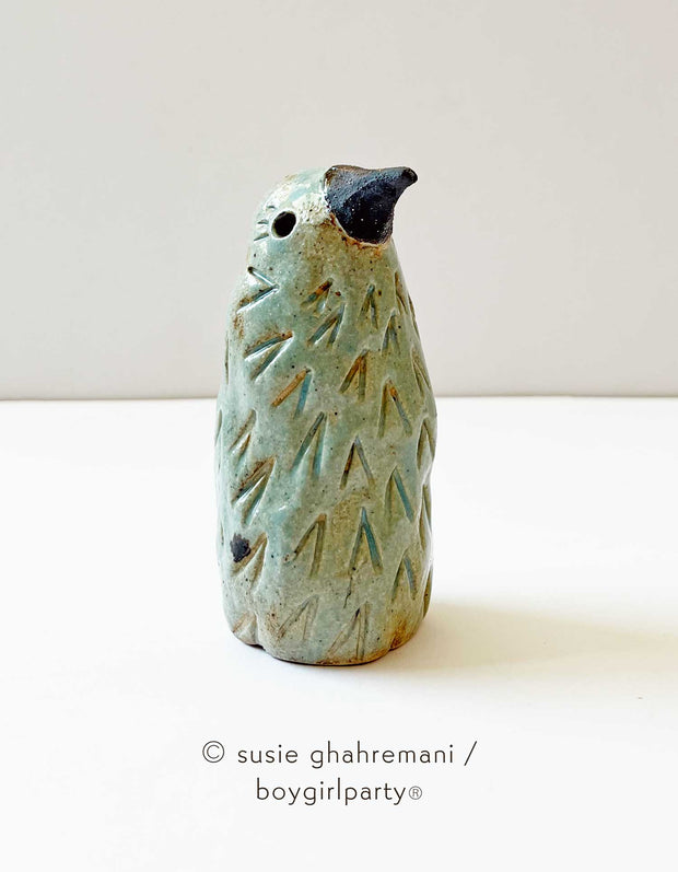 Mint green ceramic sculpture of a bird, standing without a lower body with an in set eyed and a black pointed beak