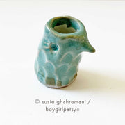 Small teal ceramic bird head with an opening for ink.