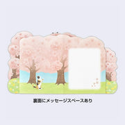 Back view of card, with an illustration of 3 cherry blossom trees and a calico cat on its hind legs looking at the falling blossoms. Next to the cat is a blank writing area.