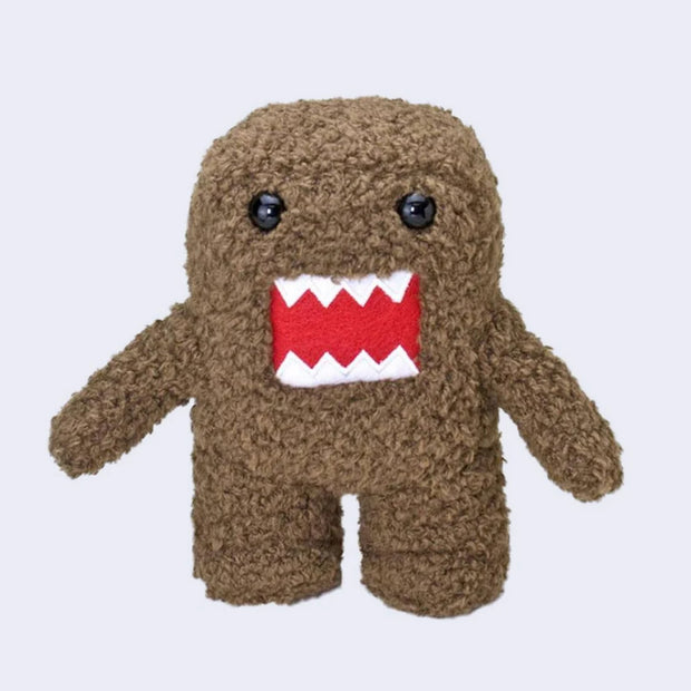 Fluffy plush doll of Domo, with brown fur, an inlayed embroidered red mouth with jagged white teeth and black beads for eyes. It stands with its arms out to its side.