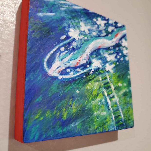 Illustration of a white and blue serpent like dragon, gliding through the sky over a large body of water with train tracks submerged underneath it with various greenery under water as well. Sides of the panel are red.