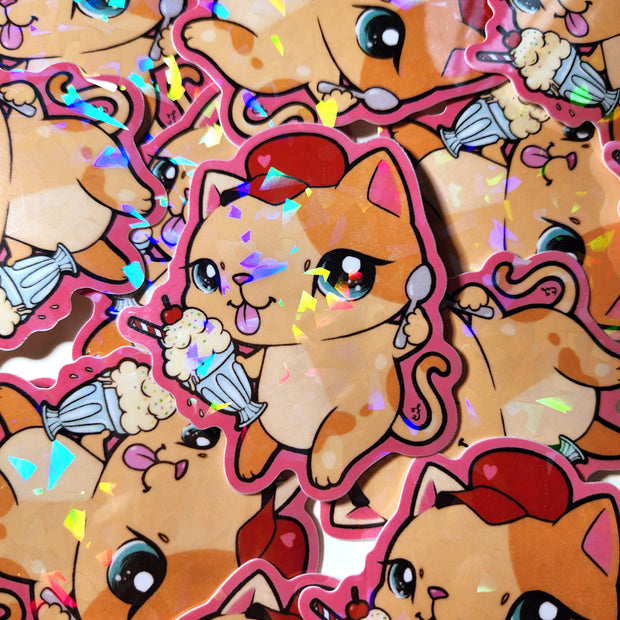 Pile of holographic stickers of the same design - an orange cartoon cat wearing a red cap and holding an ice cream sundae in one hand and a spoon in the other. It has its tongue out.