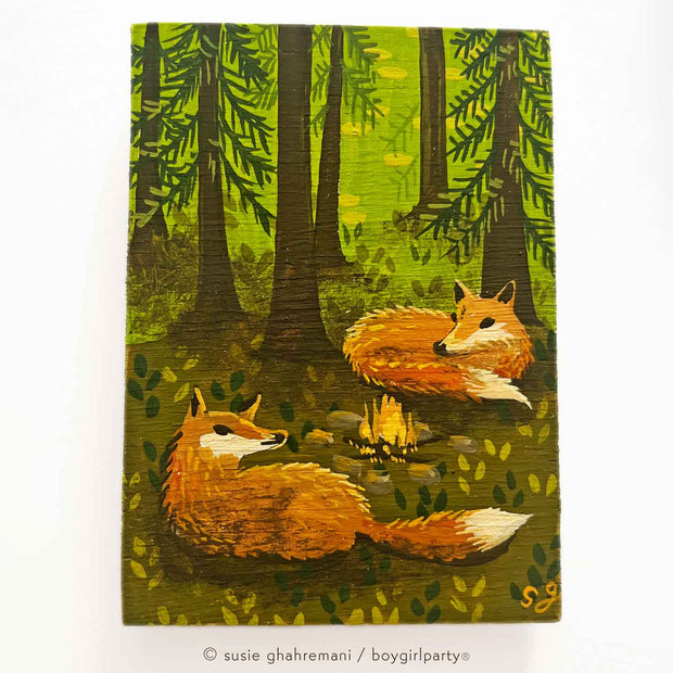 Painting of 2 foxes, laying in front of a small campfire in the middle of a forest with tall trees. Background is bright green, with the foreground mostly browns.