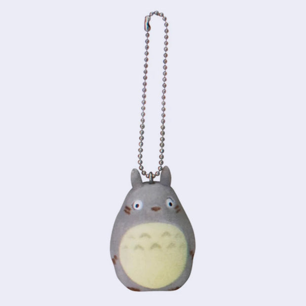 Small keychain with flocked surface of Totoro, with his arms at his sit and no mouth. 