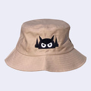 Light brown bucket hat with a black embroidered logo of a robot head, with white angry eyes.