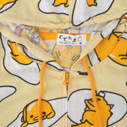 Light yellow hooded jacket with a repeating all over pattern of Gudetama, sitting on egg yolk, inside of an egg shell or wrapped in bacon. Close up.
