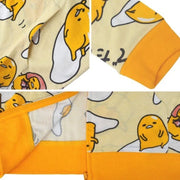 Light yellow hooded jacket with a repeating all over pattern of Gudetama, sitting on egg yolk, inside of an egg shell or wrapped in bacon. Close up.
