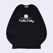 Black long sleeve shirt with a graphic in the center of Hello Kitty reading a book. Around her says "Hmmmmm.." with half the text on one side and the other half on the other. Below is a white yarn embroidered element spelling out "Hello Kitty".