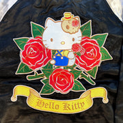 Embroidered large graphic of Hello Kitty with red roses all around her. She has a skull shaped hairpin and sits while holding a rose. A golden banner scroll is below her with "Hello Kitty" written along it.