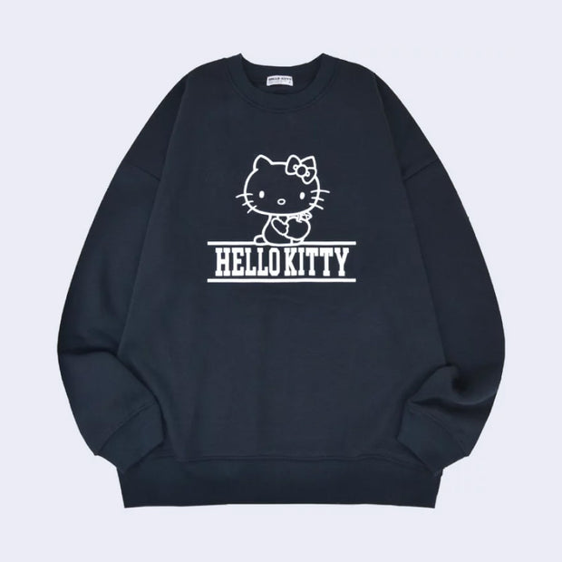 Navy blue sweatshirt with a white ink line art graphic of Hello Kitty, sitting and holding an apple in her hand. Below her is fully capitalized text that reads "Hello Kitty" in white font.