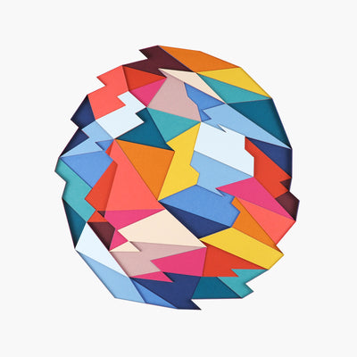 Colorful cut paper pieces puzzled into and atop of one another to create a geometric shaped ball with slightly jagged edges. White paper surrounds the enclosed shapes.