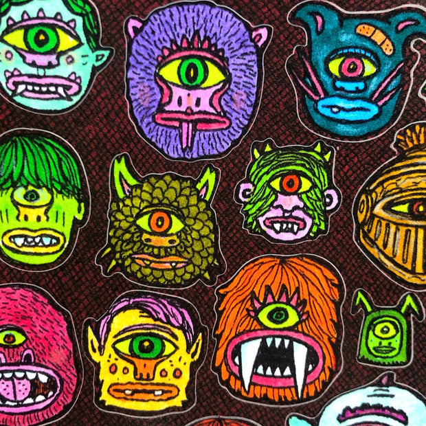 Sticker sheet with many small monster heads, all cyclopses with only one eye but a variety of other features.