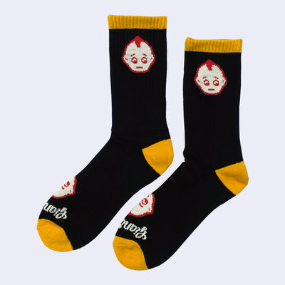 Pair of socks, mostly black with mustard yellow color accents around the calf, toe and ankle of the sock. A small kewpie head is on the ankle with another on the foot with "Giant Robot" written underneath.