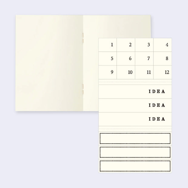 Interior of a notebook with blank ivory colored paper and a small sticker set of numbers and "idea" spaces.