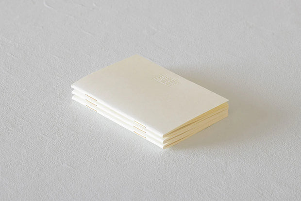 Product photo of 3 small ivory colored staple bound notebooks stacked atop on another.