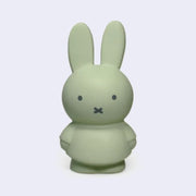 Miffy shaped coin bank, completely colored a grayish shade of green with gray eyes and mouth. She stands wearing a dress with her arms at her sides.